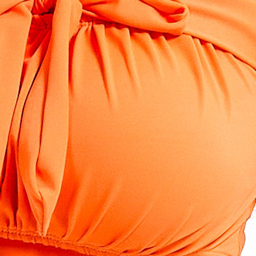 一個人的肚皮特寫,可能是懷孕了,穿著 橙色背心 MIX&MATCH 泳衣上身 <23641739>,上身有蝴蝶結或結頭。褶皺的布料舒適地垂疊在圓潤的外形上,並配有可拆卸的胸墊。.