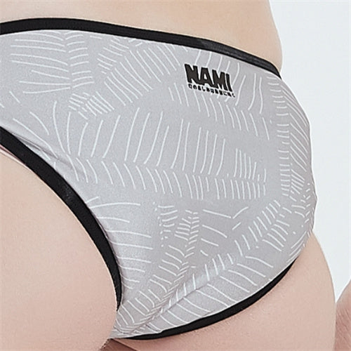 特寫穿著灰色-MIX&MATCH泳衣下身 <24061473>的人,淺灰色布料搭配白色葉子圖案,黑色飾邊,腰部附近以黑色印上 NAMI 品牌名稱。.