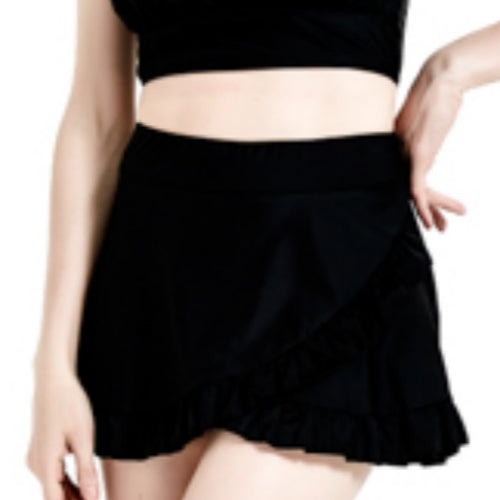 一個身穿黑色作物上衣和黑色荷葉邊迷你裙的人,一隻手放在臀部,在白色背景下從中腰到大腿上部顯示。.