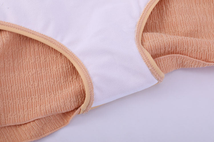 橙色高腰裙MIX&MATCH泳衣下身<24101625>特寫,顯示白色布料搭配米色彈性飾邊,背景為桃紅色質感布料,突顯縫線與布料細節。.