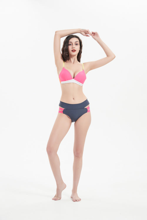 一名女子赤腳站在白色背景上,身穿粉黃色比基尼上衣,上面印有黑色搭帶MIX&MATCH泳衣下身<24151599>。一隻手臂高舉過頭,另一隻手臂搭在頭上,展現出這套平實的泳衣。.