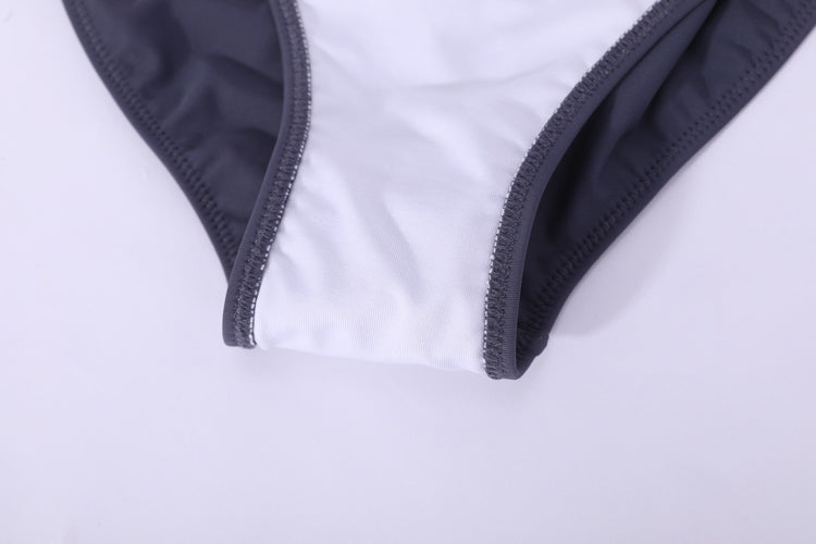 黑色搭帶MIX&MATCH泳衣下身 <24151599>正面特寫,黑色邊緣與白色中間面板,平放在光面上,展現顯瘦泳裝設計。.