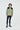A person with medium-length brown hair wearing an 杏色2合1撥水防風外套 <20621678-12>, black leggings, and black athletic shoes, standing against a plain white background，展現都會休閒風格。.