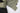 杏色 2合1撥水防風外套 <20621678-12>特寫，正面拉鏈部分拉開，露出橄欖綠色的保暖抓毛內膽。左側為黑色，右側和內膽為橄欖綠色。.