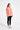 Person wearing a coral jacket with black accents on a white background