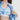 棕色長髮的女子打開藍白拼接外套，露出天藍色 4 件套裝運動泳衣 <21211824> 的熱帶藍綠色調。純白的背景突顯出毫不費力的夏日運動服風格。.