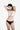 一位女士佩戴著杏色-MIX&MATCH泳衣上身 <23501585>，在素白背景下擺出造型，雙手抱頭，低頭看向側邊。.