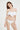 一位棕色長髮的女性站在素色背景下，閉著眼睛微笑。她身著 NAMI Bikini，搭配白色-MIX&MATCH泳衣下身 <24051531>，側邊系帶、高開叉下身和褶邊上身細節。.