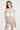 一位棕色長髮的女性身穿白色褶邊 NAMI Bikini 上衣和天藍色高叉三角 MIX&MATCH泳衣下身 <24051623>，站在純白背景下微微笑著。.