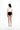 一名女子面對鏡頭赤腳站立，身穿白色短袖Crop Top和黑色鏤空MIX&MATCH泳衣下身<24161720>，背部系有花邊，在白色背景下展現簡約時尚泳裝風格。.