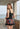 Woman wearing a black swimsuit with colorful geometric patterned skirt on a balcony with ocean view