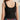 Person wearing a black tank top with a brand logo on the back, standing against a neutral background.