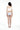 一名女子赤腳面向遠方站立，身穿白色一字肩日本製泳衣 <450301-WT> crop top 和藍色碎花比基尼下裝，背景為純白。.