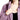 一位女士正在拉開粉紫色彈性透氣撥水防風外套 <20221548-50>的部分拉鍊，露出下面的黑色上衣。畫面重點在她的脖子、肩膀和上胸部。.